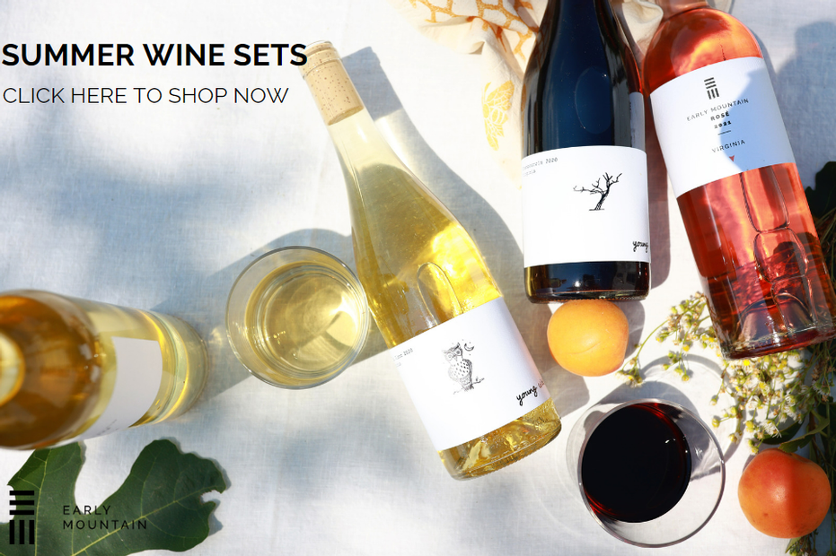 Summer Wine Sets - Click to view our options (image shows four bottles of wine on a table from above, with two glasses of wine, a clementine, and summer florals))